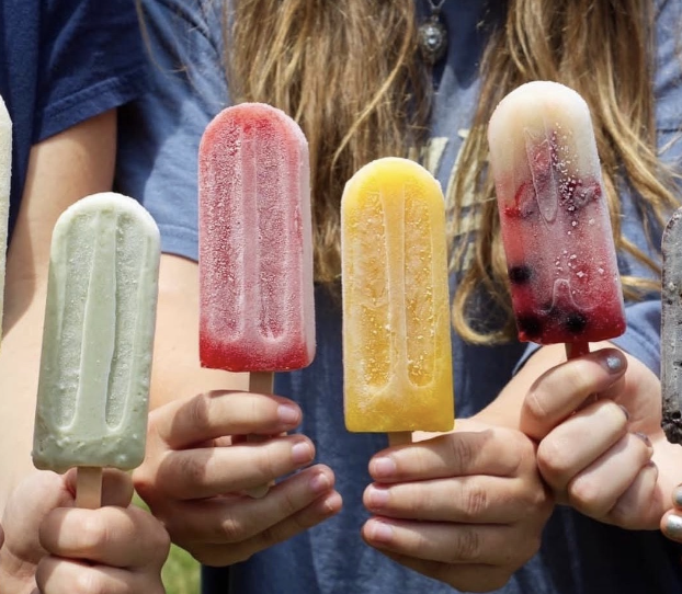 Four kids holding up colorful PopCentric ice pops outdoors