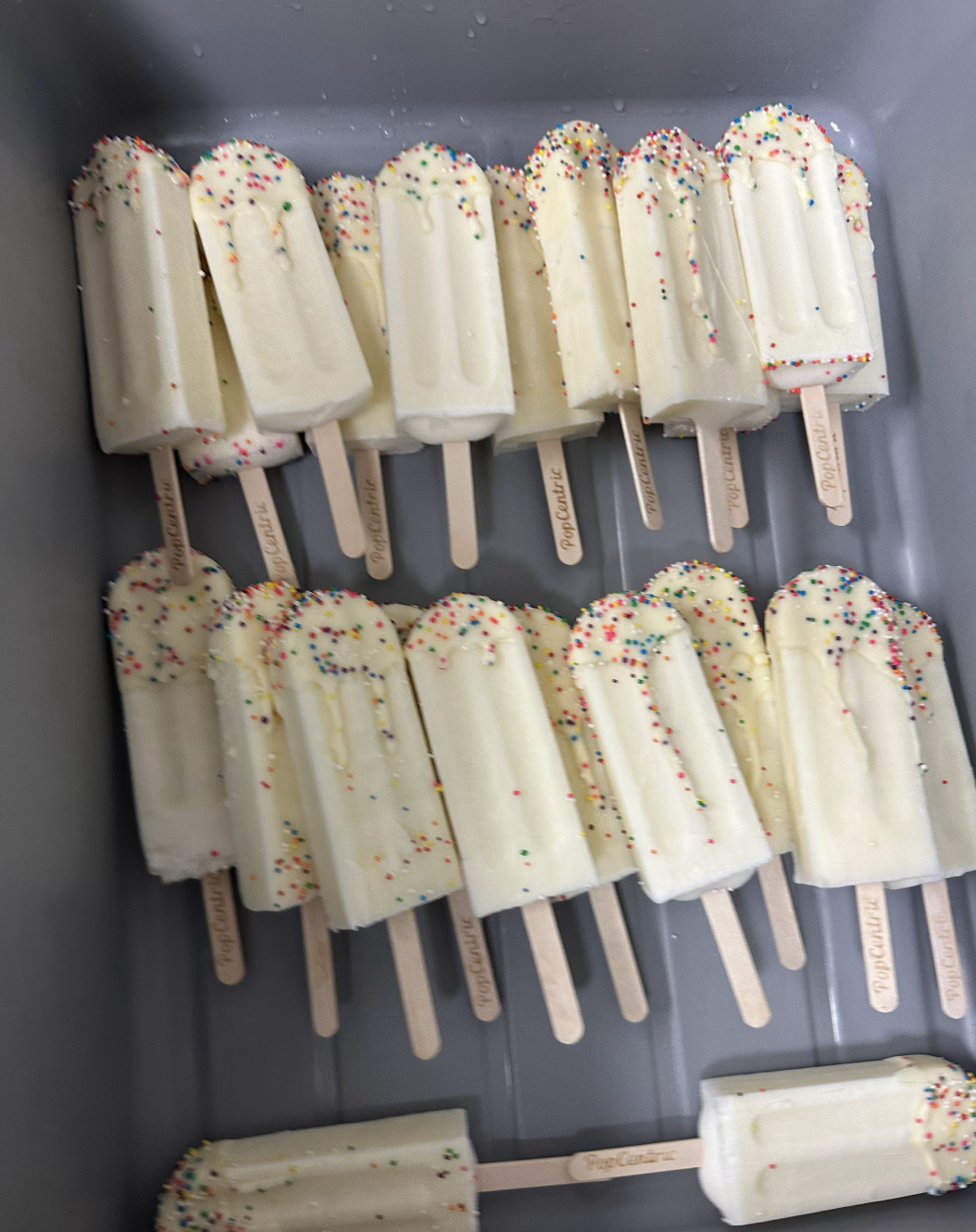 Vanilla ice pops dipped in rainbow sprinkles arranged in a cooler